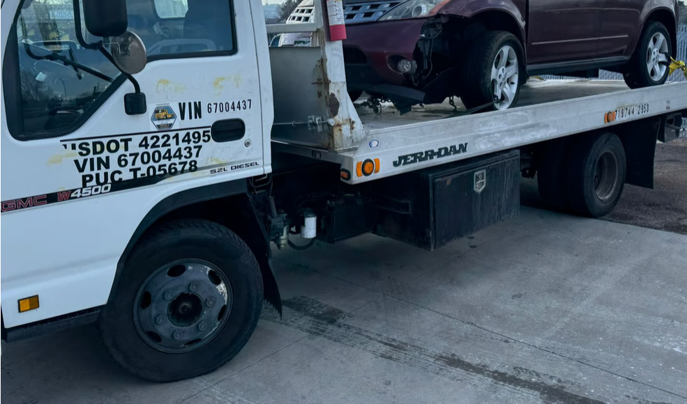 Flatbed tow truck carrying a pickup truck in Colorado Springs